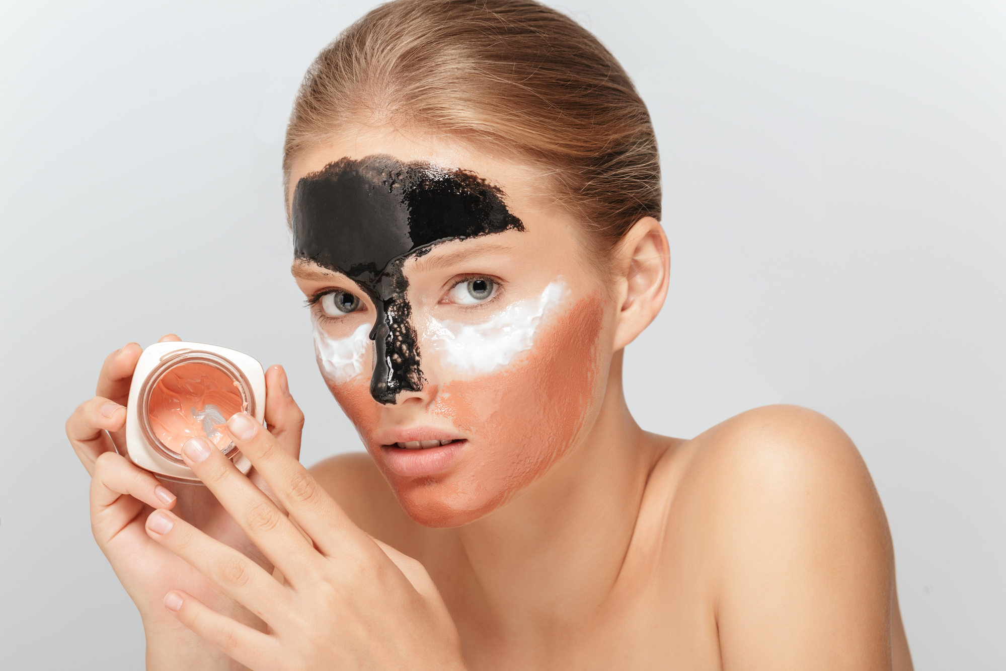 A woman wearing different colors and types of exfoliating masks.