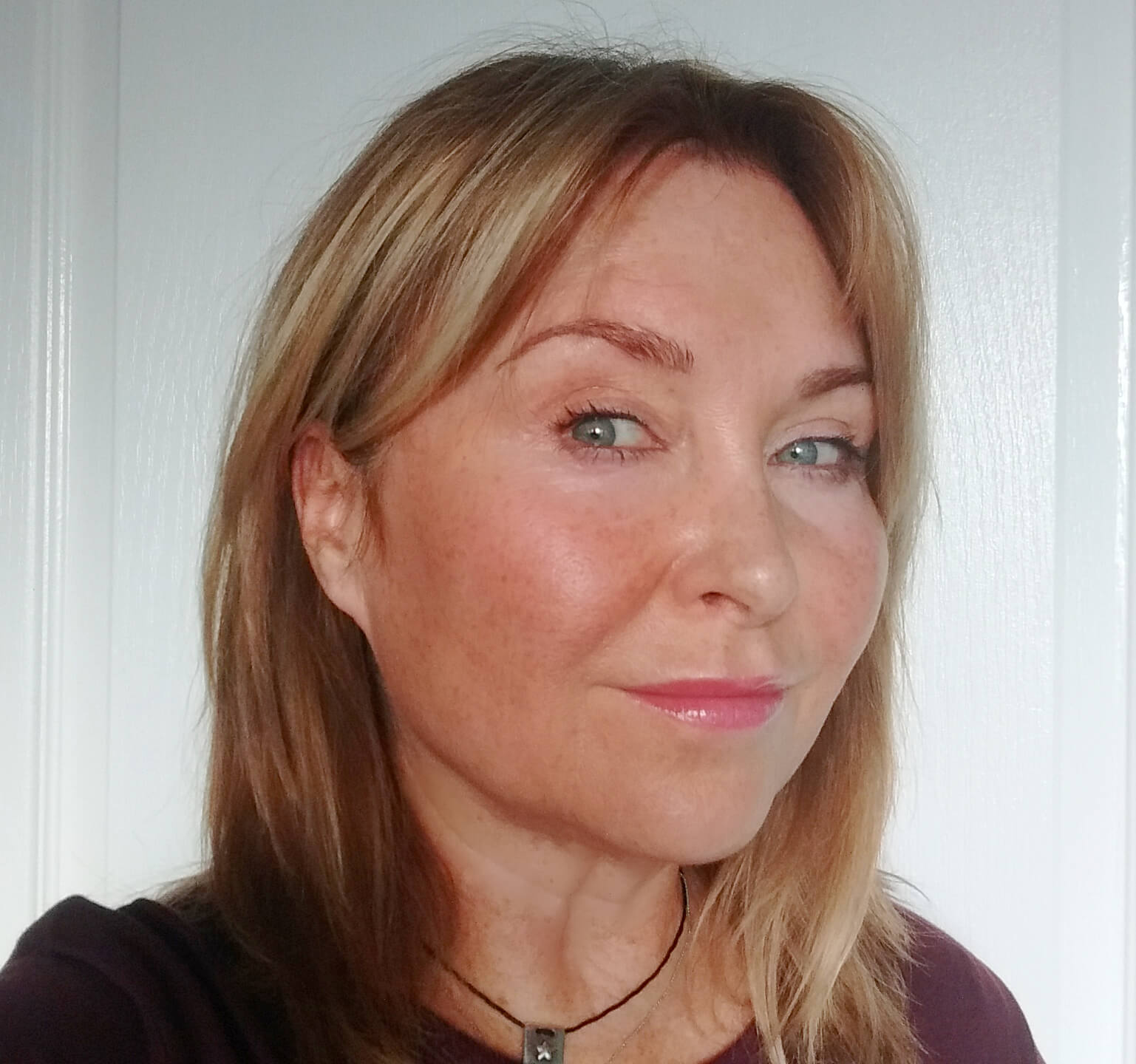 BB cream applied to one cheek showing added warmth on fair, freckled mature skin