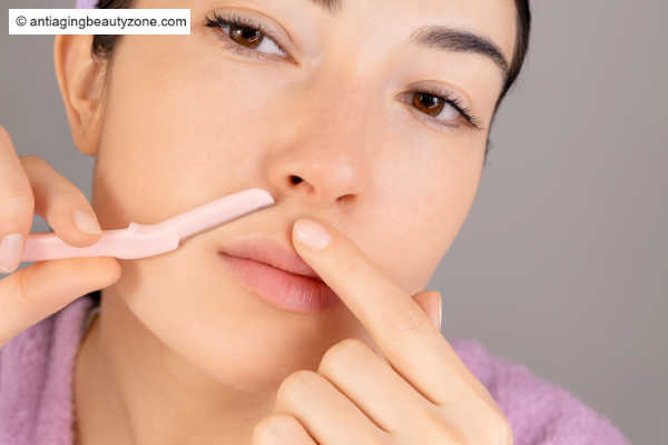 A woman dermaplane her upper lip. Does dermaplaning smooth skin? Yes.