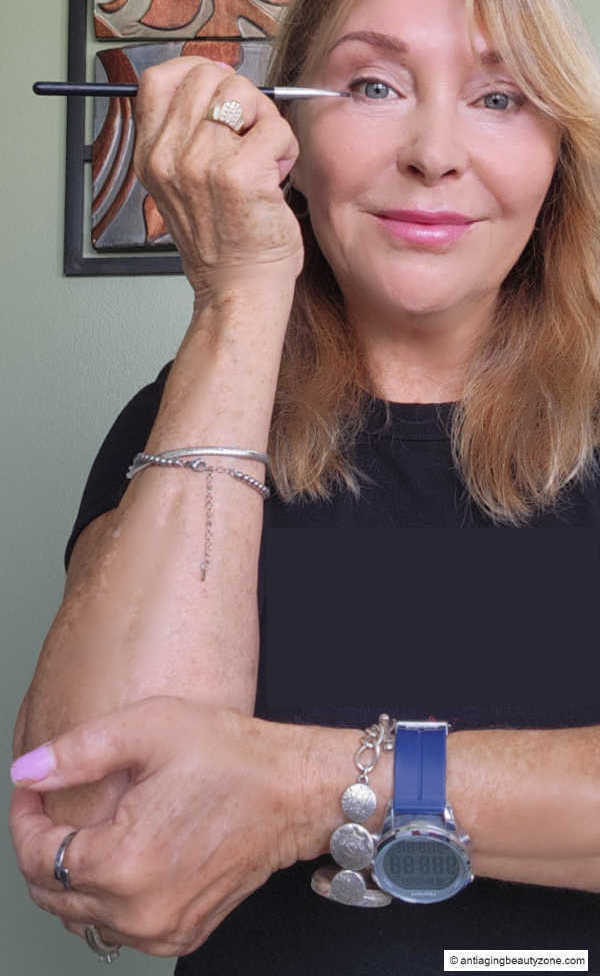Linda supporting her eyeliner arm at the elbow with her opposite hand for steadier eye makeup application.