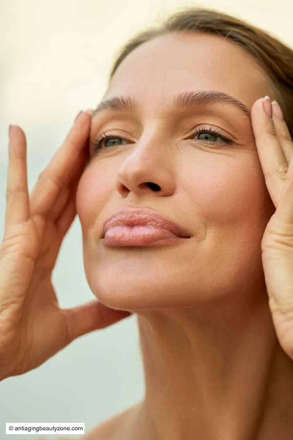 Facial exercise to tone and lift skin naturally Woman performing facial exercise by gently lifting skin near temples