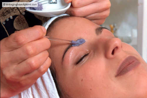 Close-up of a woman having her eyebrows dyed for a darker, more defined look.