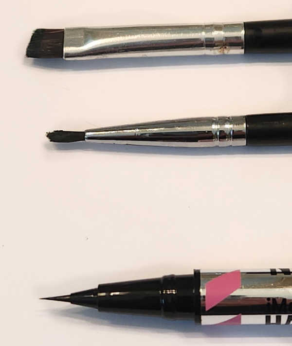 Flat angled gel eyeliner brush, pointed gel eyeliner brush, and fine liquid eyeliner tip side by side