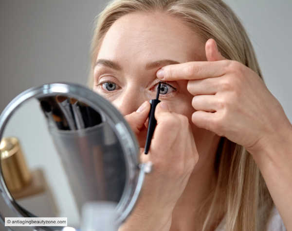 How to tightline the upper lash line for subtle definition for aging eyes. Woman applying eyeliner to the upper waterline for a soft tightlining effect.