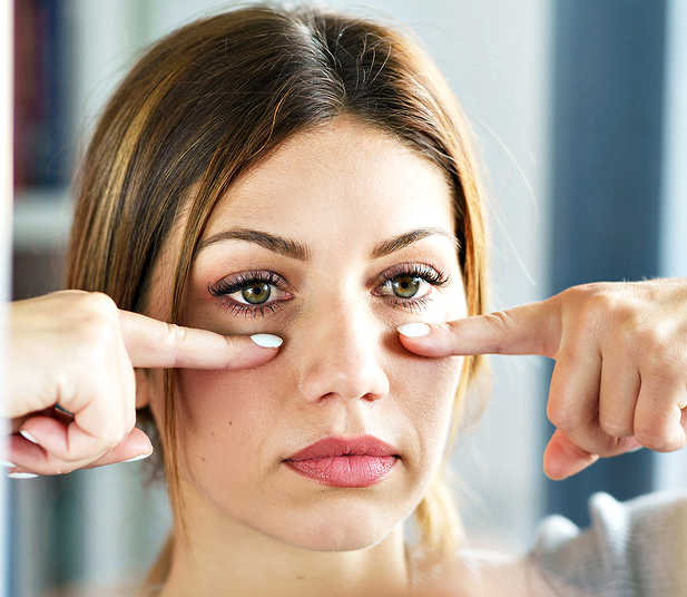 Exercising helps firm up sagging facial muscles for a less aged face. A woman performing facial muscle toning exercises to lift and tighten facial muscles.