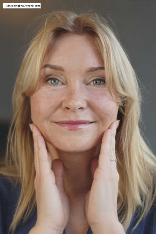 Gentle lower-face routine for jowls (no gadgets) Woman gently lifting her jawline with both hands—example of a gentle lower-face routine for jowls.