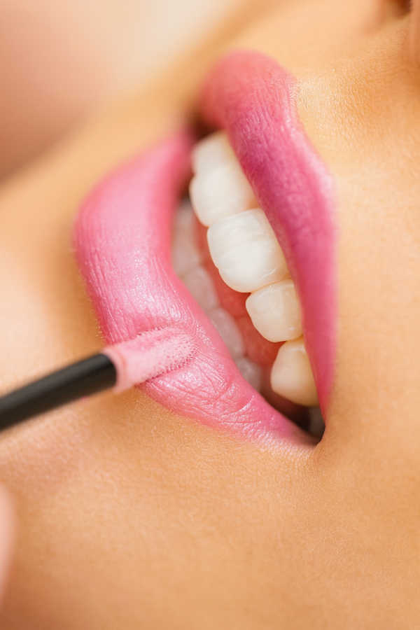 Close-up of pink lip gloss being applied to smooth lips