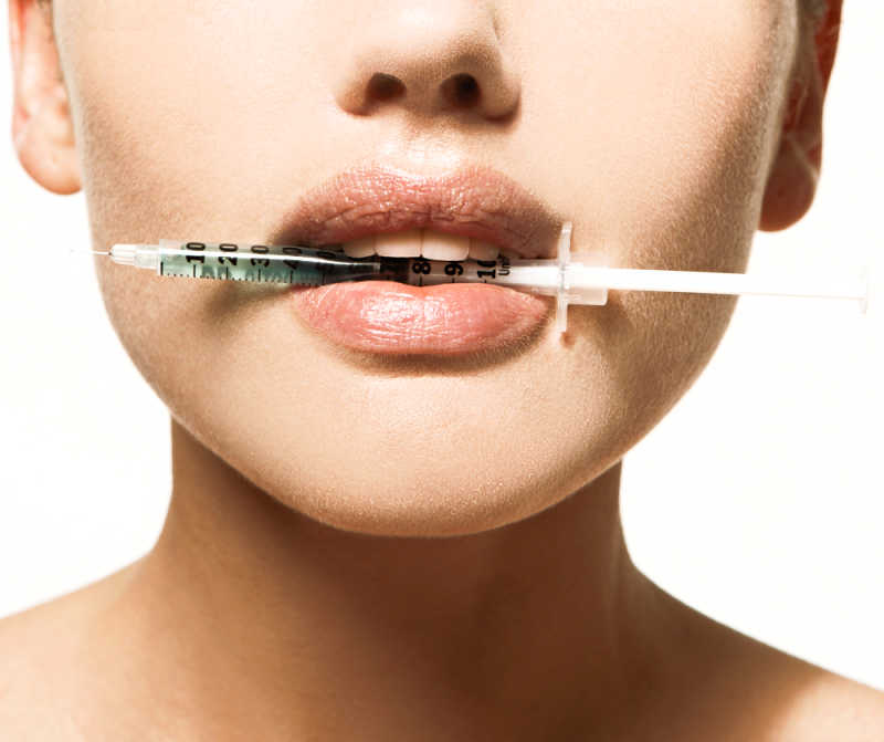 Lip injection vs lip filler. Woman holding lip injection syringe in her mouth.