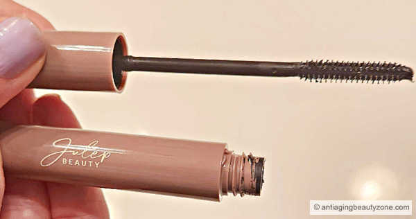 Linda Robison holding a mascara tube and wand, showcasing the best mascara for older women.