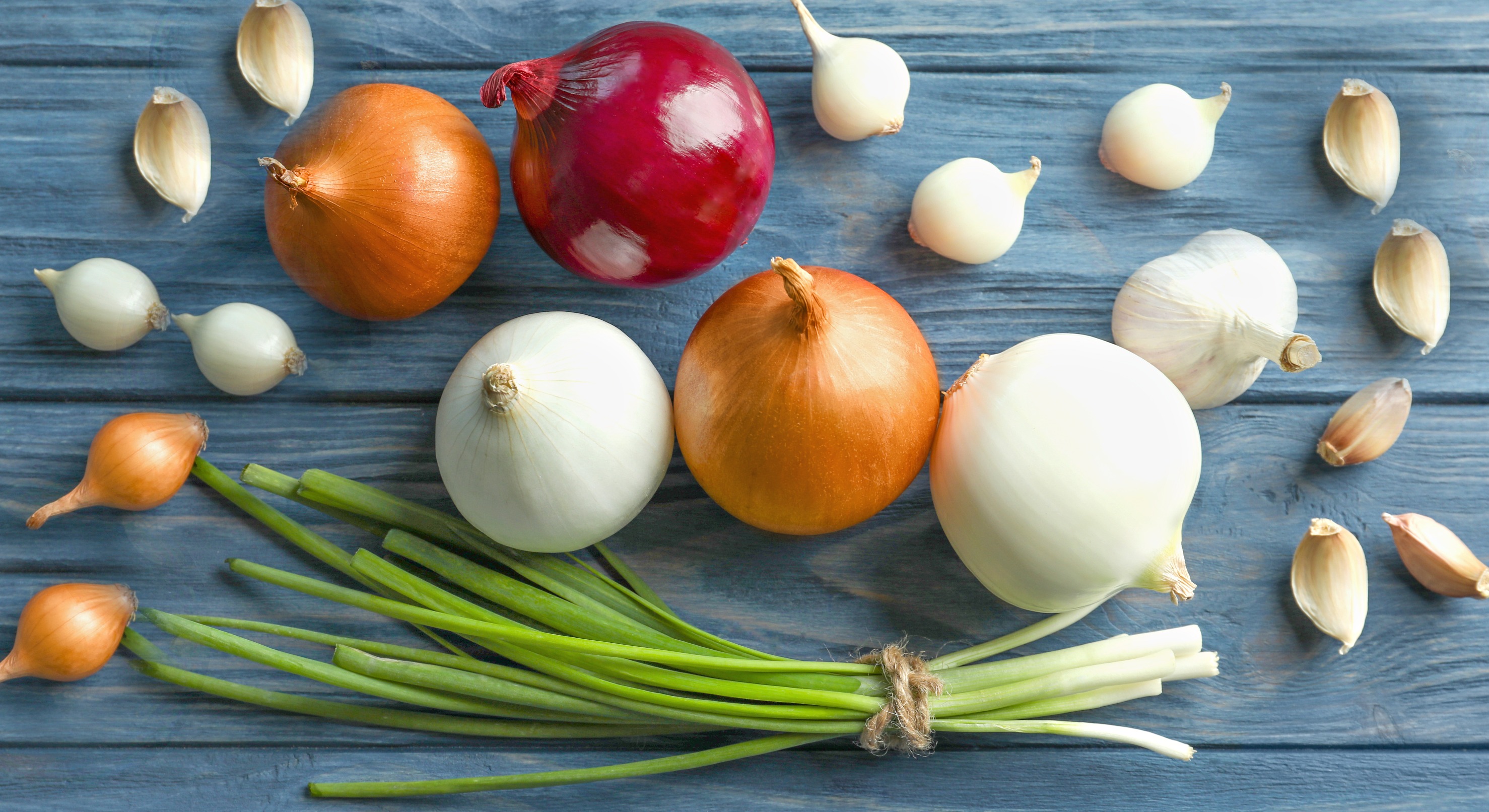 Fresh onions and garlic on a wooden surface—rich in sulfur compounds that support healthy, youthful skin