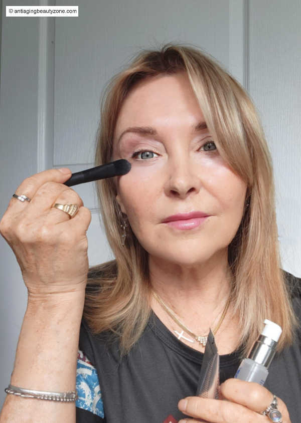 applying tightening eye serum under eyes with brush to reduce puffiness