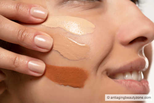 Applying skin tint is all about getting a natural finish. Woman test different shades of skin tints on her cheek.