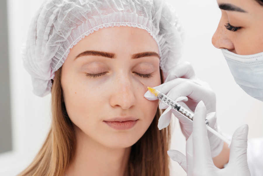 A woman getting filler for puffy eyes. Also called tear trough injections.