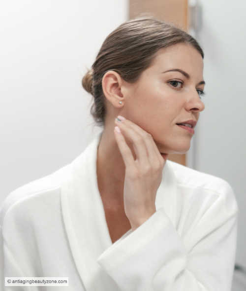 The benefits of enzyme facials are limited. A woman looking in mirror after a enzyme facial.