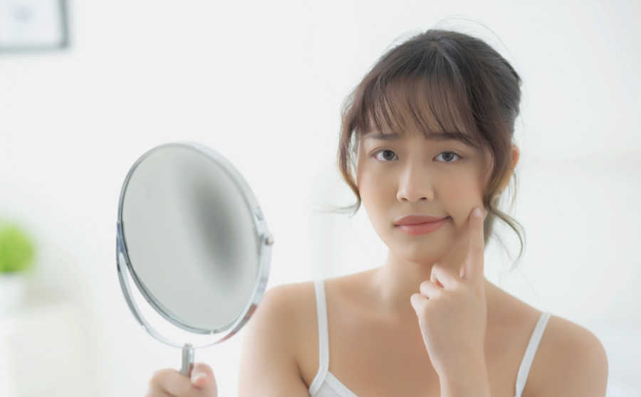 Why isn't my Botox lasting longer? Disappointed woman looking at mirror.